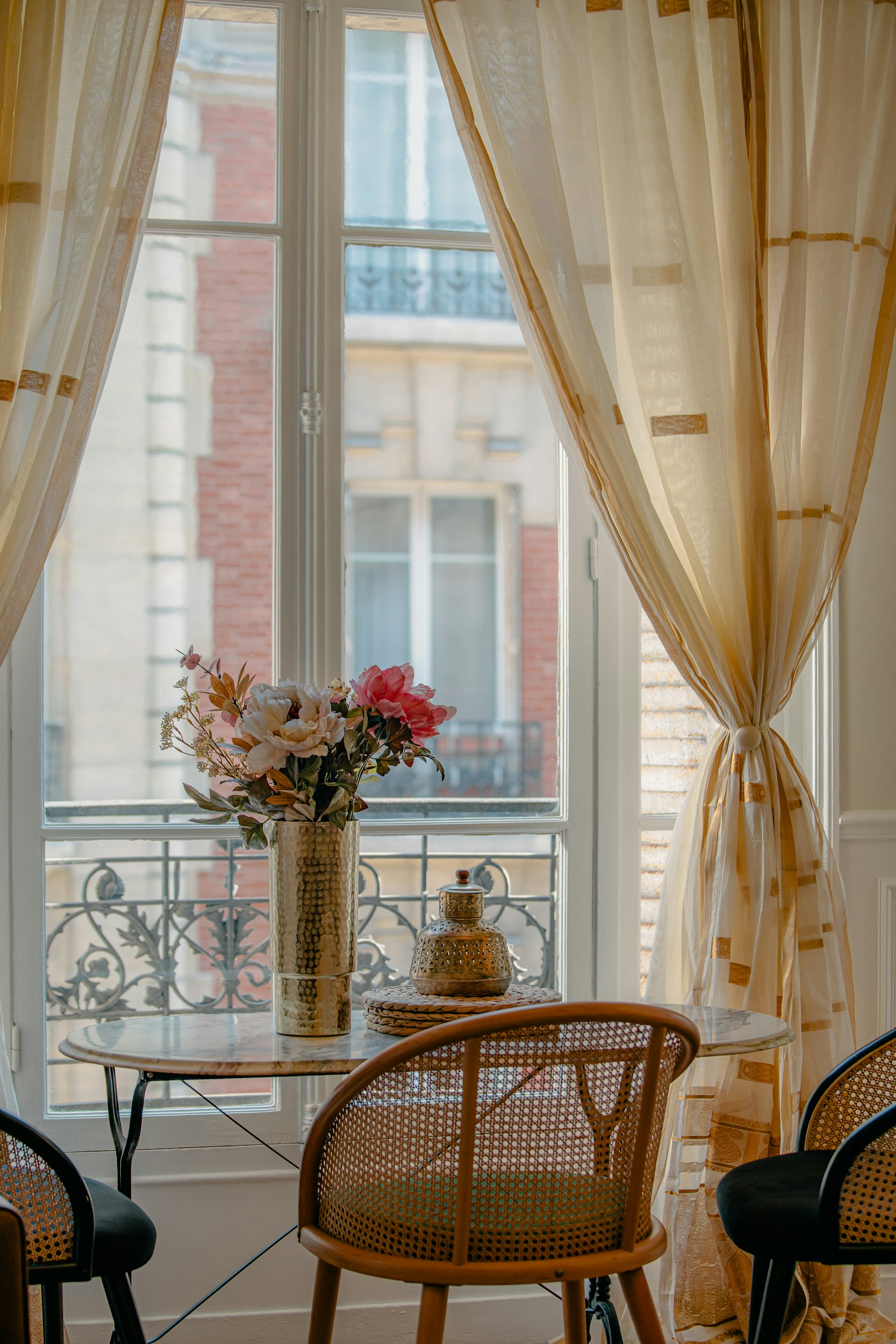 Table dressée devant une fenêtre ouverte, lumière du matin dans un appartement parisien
